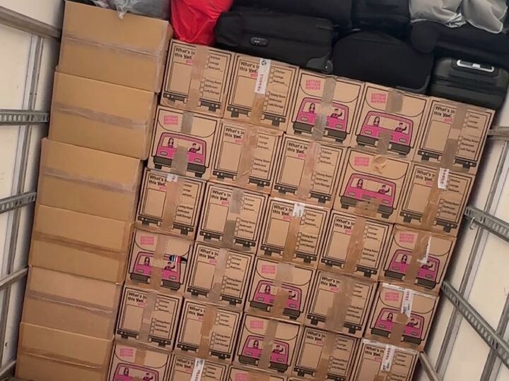 A wall of labelled moving boxes and suitcases stacked neatly inside the van