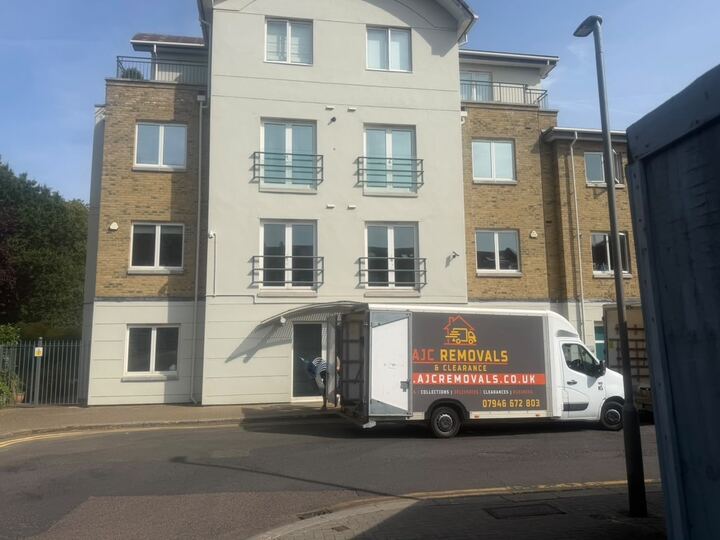 AJC Removals van with its doors open outside a block of flats during a move